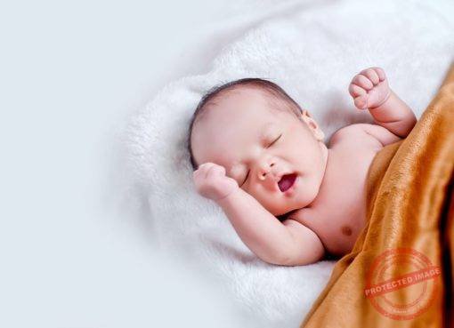baby lying on white fur with brown blanket