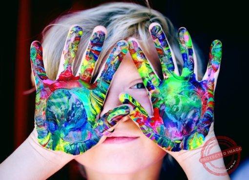 a kid with multicolored hand paint
